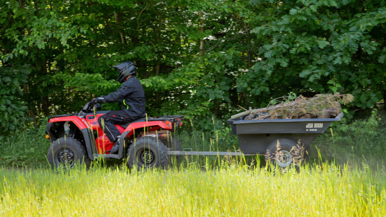 Un cavalier transportant du foin à l'arrière d'un éleveur Honda