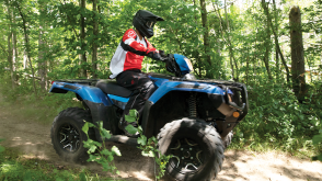 A rider on a Honda Rubicon going down a dirt road 