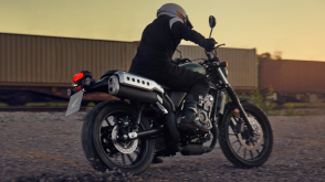 Un cavalier sur une Honda SCL500 à côté d'un train