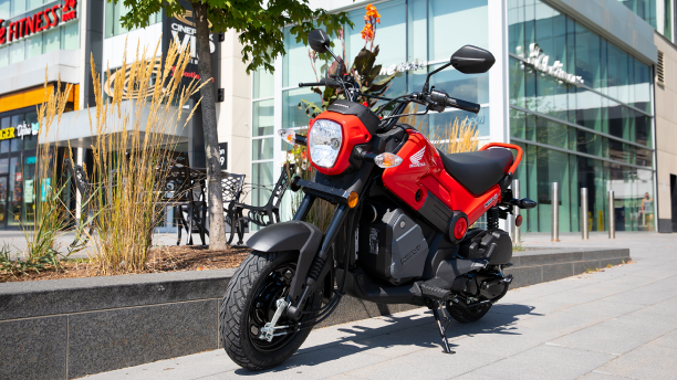 A parked Honda Navi outside of an urban building 