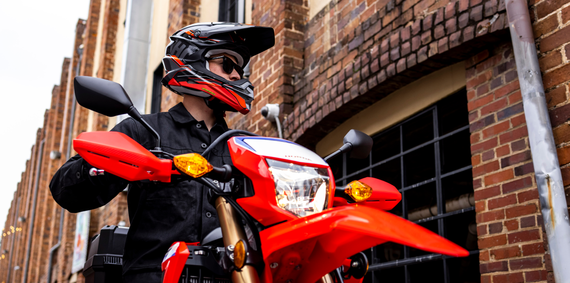 A close-up of a person driving the Honda CRF300L on a city street