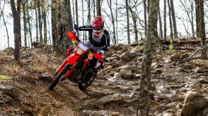 Une vue sur l'angle frontal d'une personne chevauchant la Honda CRF300L dans la forêt