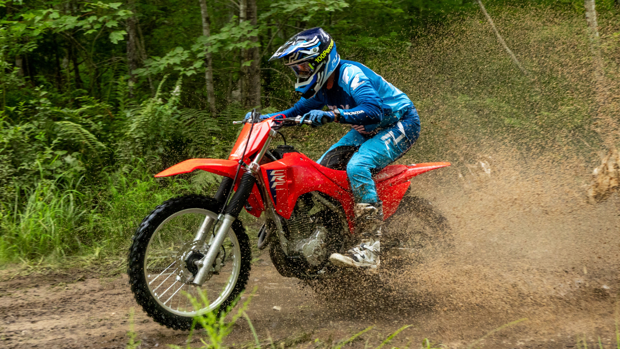 Rider on CRF300F going left. Forest landscape in background.