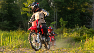 Young rider and dirt road. Front facing. Woodland background.