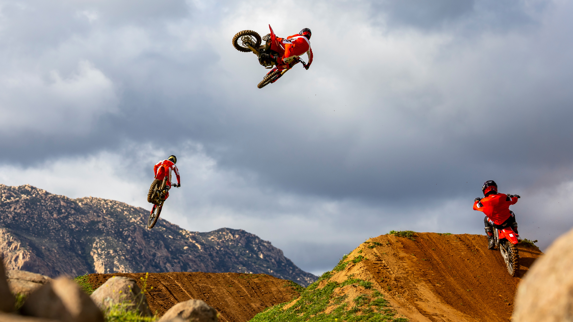 Vue arrière des cavaliers effectuant des sauts sur une piste en terre.
