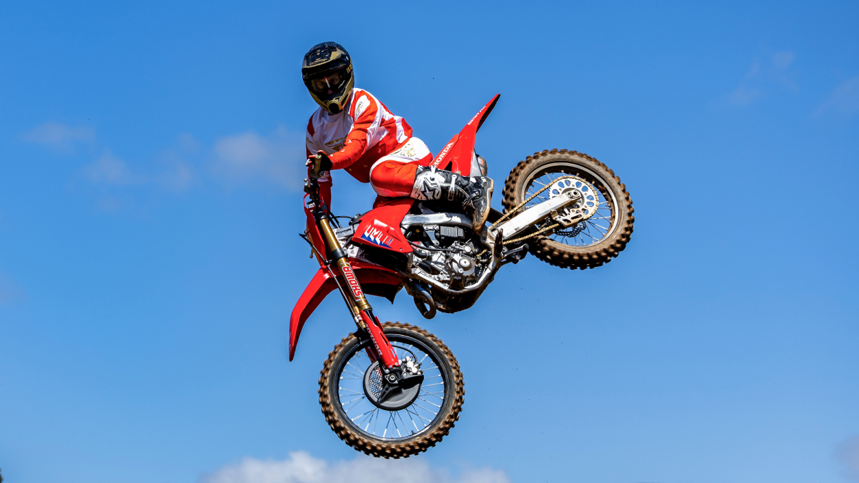 Un motard en plein vol. Ciel bleu en arrière-plan.