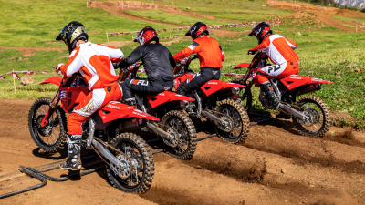 Rear view of lineup of riders on motorcycles on dirt track.