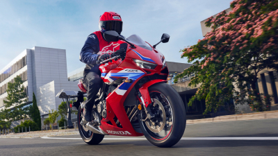 Rider on CBR650R E-Clutch going right on road. City landscape in background.