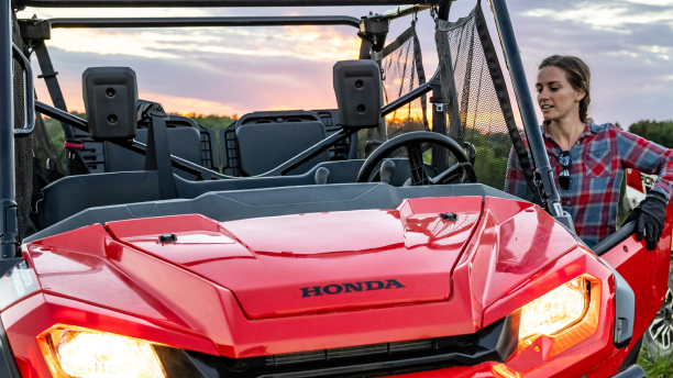 a woman standing beside a red Honda ATV/une femme debout à côté d’un VTT Honda rouge