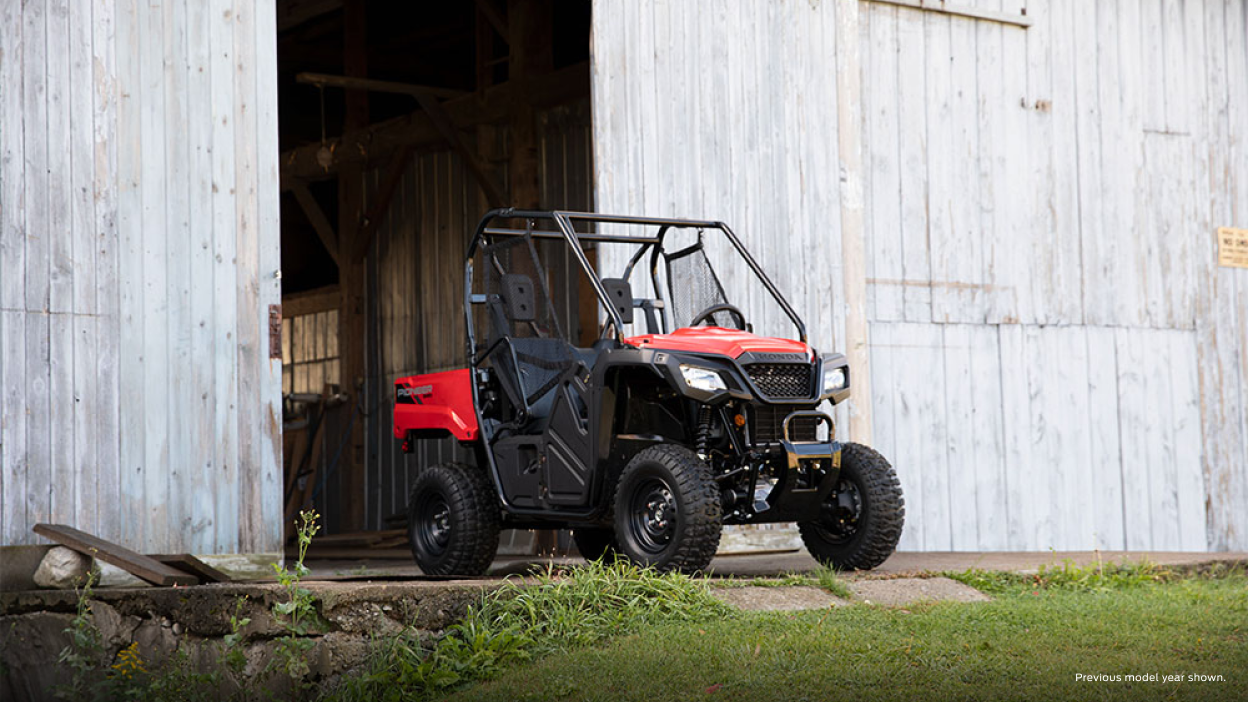 A parked Honda Pioneer 520 outside of a building 
