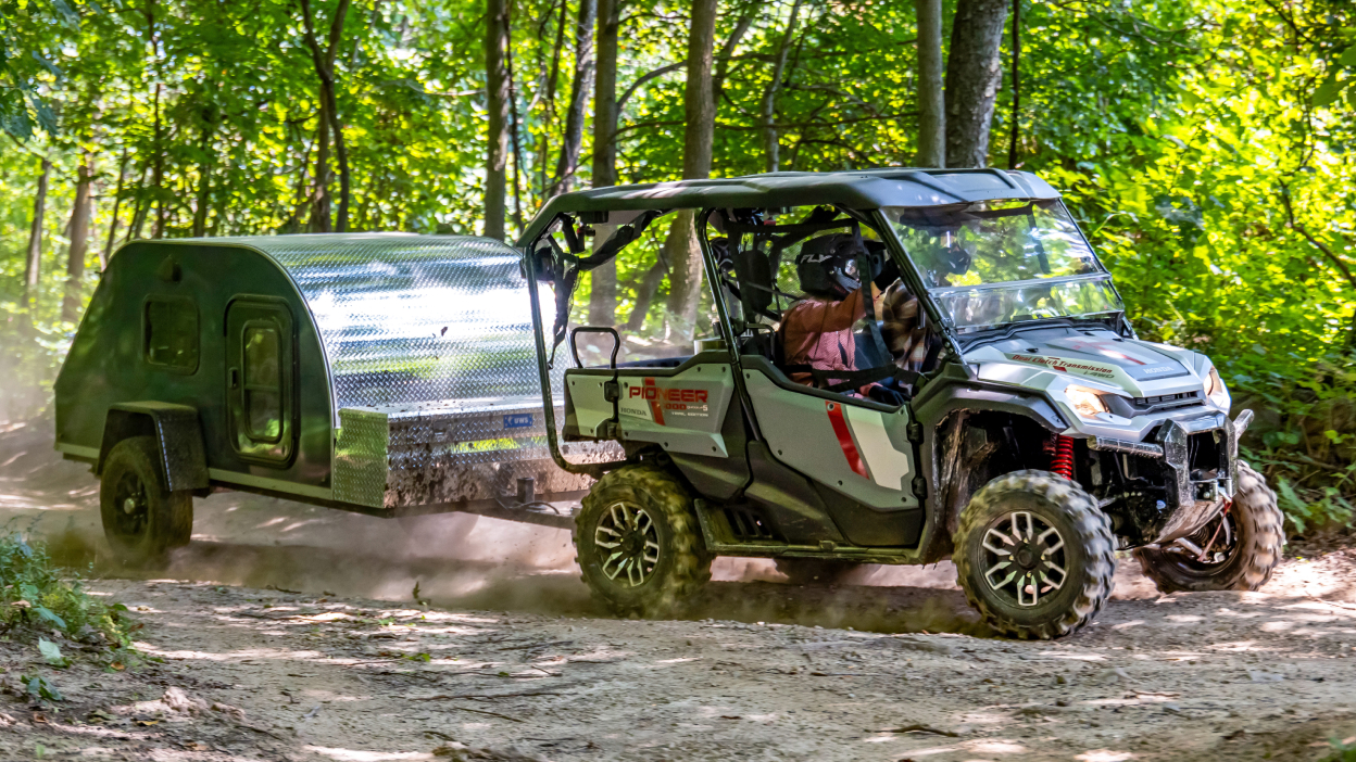 Pioneer front facing, towing trailer through forest.