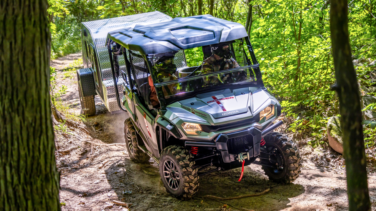 Pionnier tournant à gauche sur un chemin de terre. Remorque de remorquage. Forêt en arrière-plan.